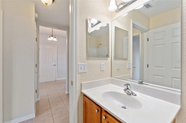 bathroom with vanity, a chandelier, a textured ceiling, and tile patterned flooring