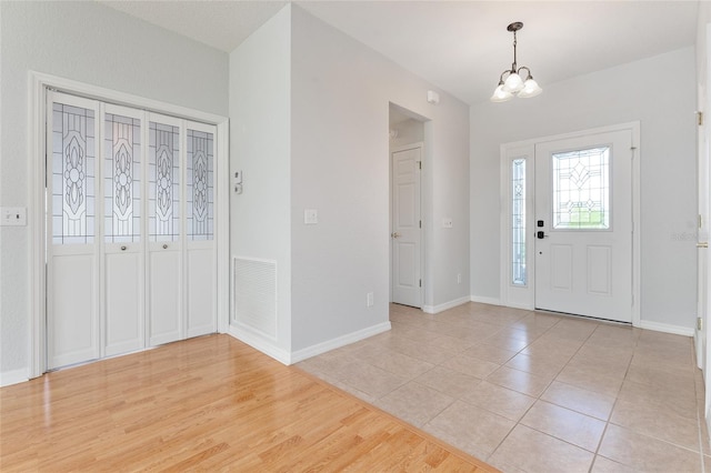 entrance foyer with light hardwood / wood-style floors and a notable chandelier