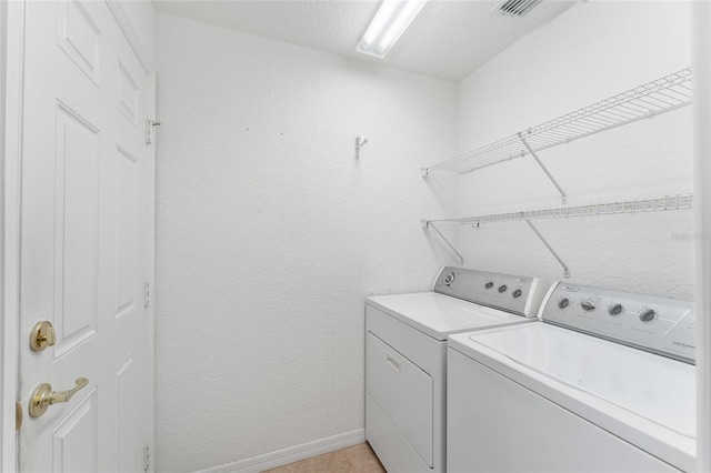 washroom with a textured ceiling and washer and clothes dryer