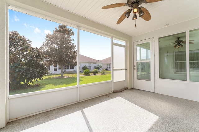 unfurnished sunroom featuring ceiling fan and a wealth of natural light