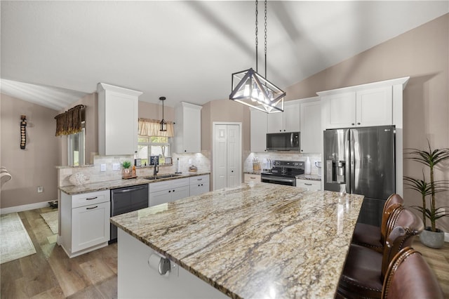 kitchen featuring black appliances, white cabinets, sink, decorative light fixtures, and light hardwood / wood-style floors