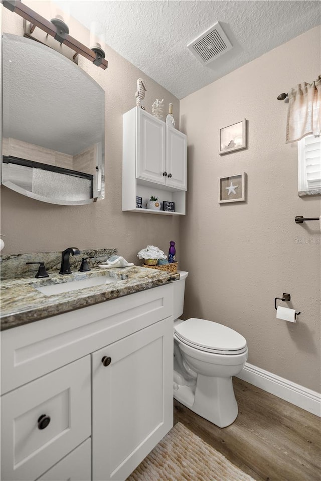 10291 SE 42nd Ter, Belleview, FL 34420 - bathroom with wood finished floors, toilet, vanity, baseboards, and a textured ceiling