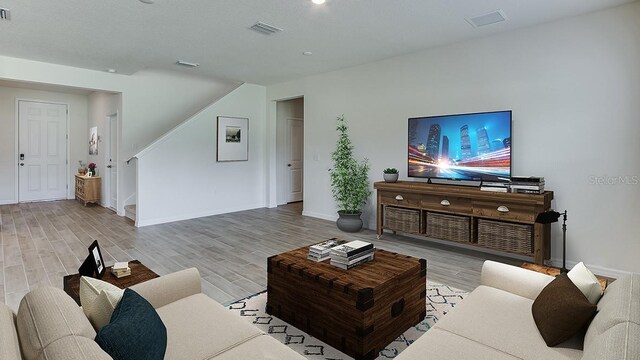 living room with stairs, wood finished floors, visible vents, and baseboards