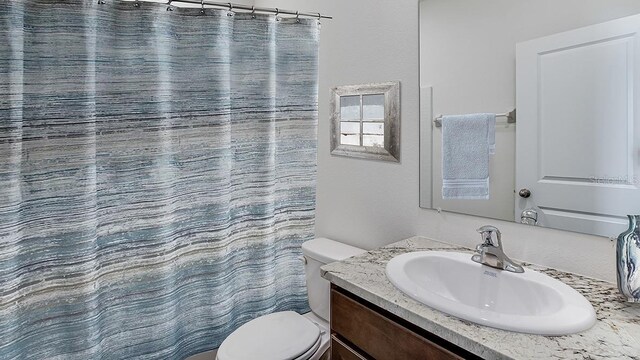 bathroom with toilet, curtained shower, and vanity