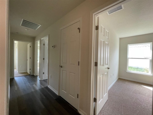 hall featuring a textured ceiling and dark hardwood / wood-style floors