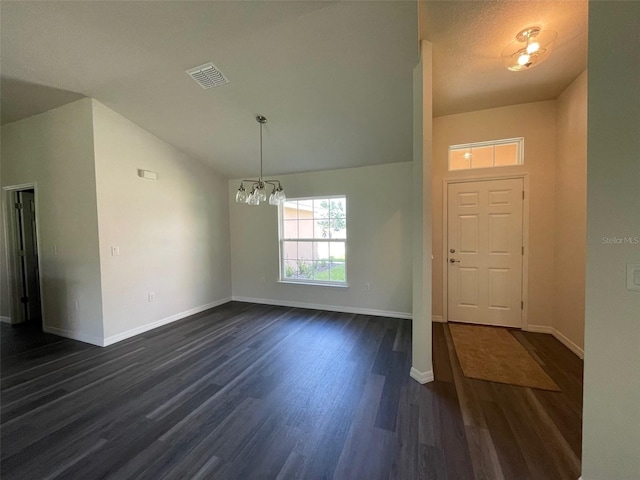 foyer with an inviting chandelier, dark hardwood / wood-style flooring, a textured ceiling, and vaulted ceiling