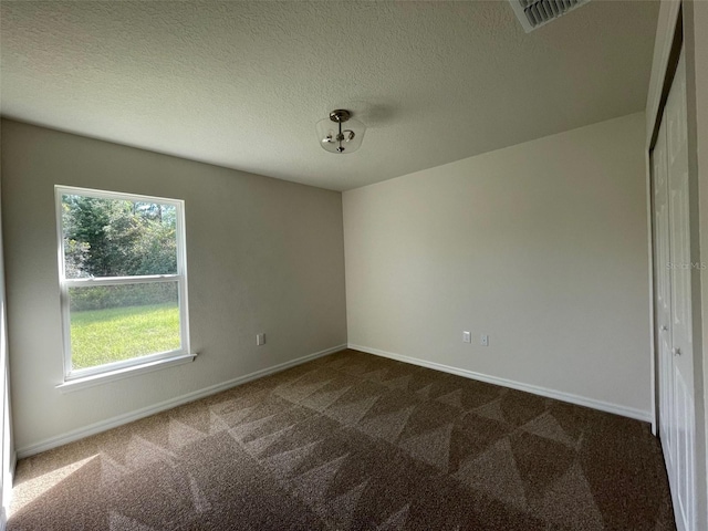 empty room featuring dark colored carpet and a textured ceiling