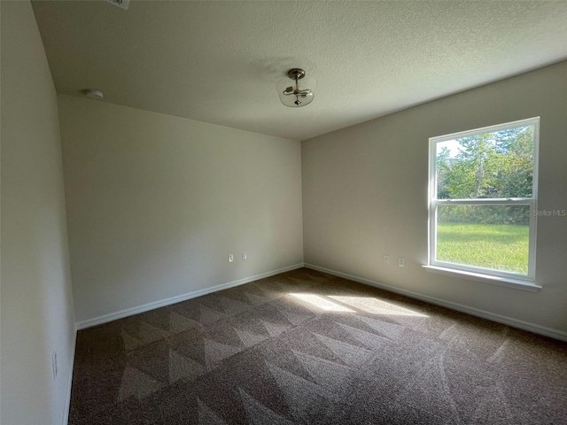 carpeted empty room with a textured ceiling