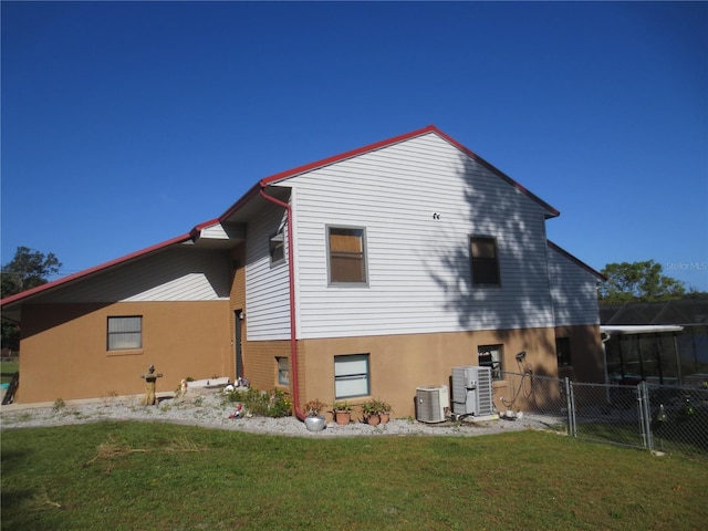 rear view of property with central AC and a yard