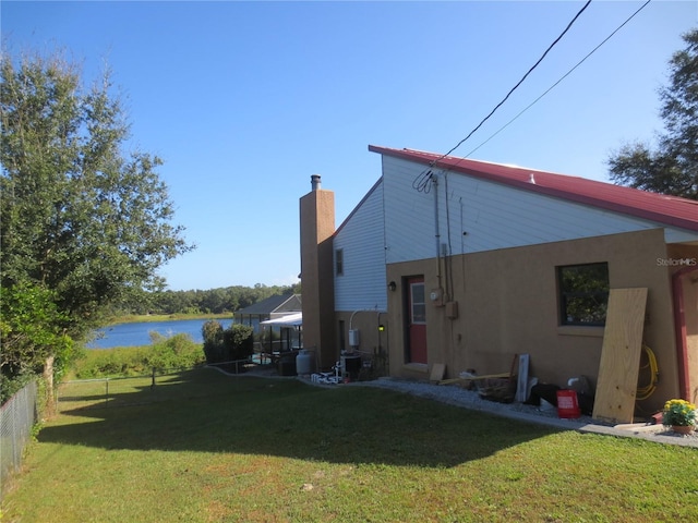 back of house featuring a yard and a water view