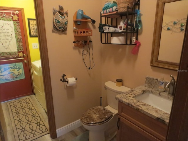 bathroom with toilet, washer / clothes dryer, vanity, and wood-type flooring