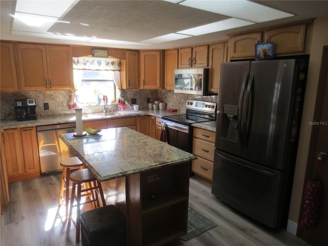 kitchen with tasteful backsplash, appliances with stainless steel finishes, a kitchen bar, a center island, and light hardwood / wood-style flooring