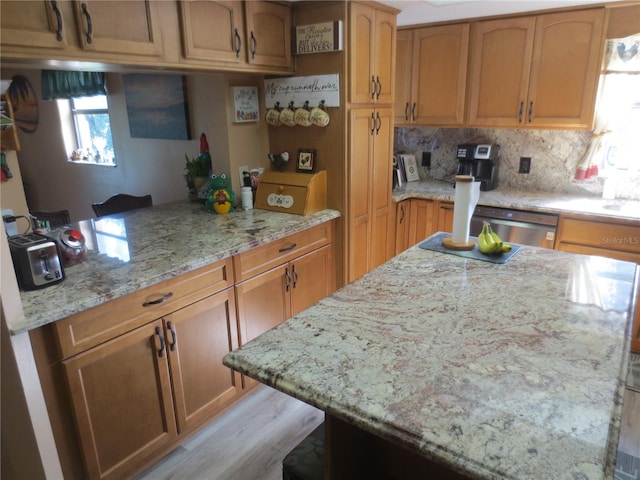 kitchen featuring stainless steel dishwasher, light stone countertops, and tasteful backsplash