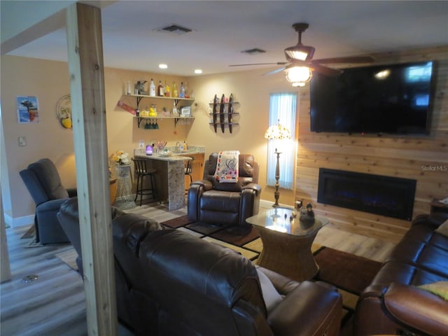 living room featuring bar area, wood-type flooring, and ceiling fan