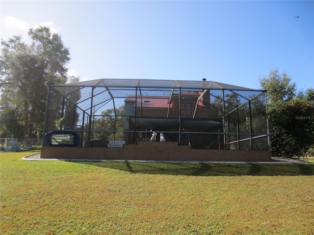 rear view of house featuring a yard and glass enclosure