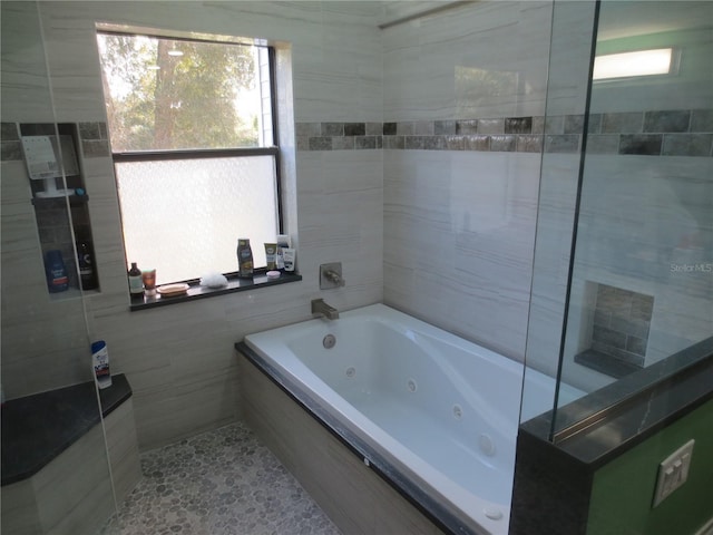 bathroom featuring tile walls and tiled bath