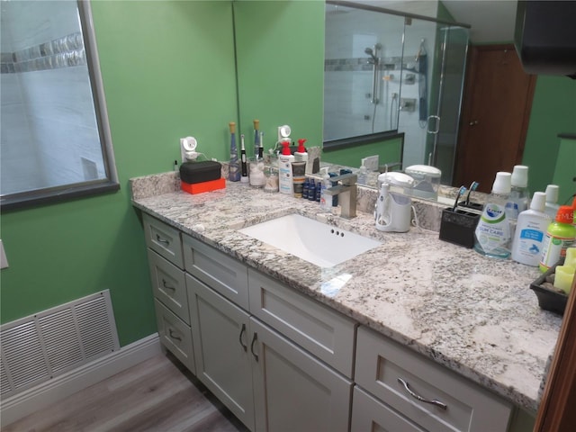 bathroom with vanity, hardwood / wood-style floors, and a shower with door