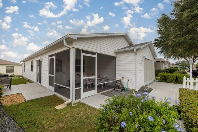 rear view of property featuring a yard, a patio, and a sunroom