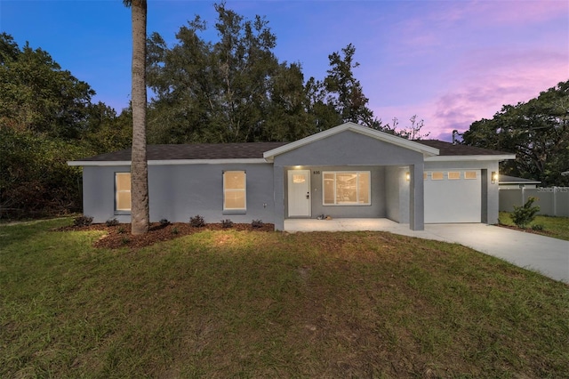 ranch-style home featuring a garage and a lawn