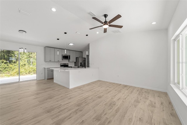 kitchen featuring gray cabinetry, light wood-type flooring, hanging light fixtures, stainless steel appliances, and lofted ceiling