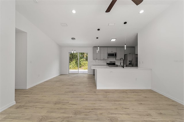 kitchen with gray cabinetry, kitchen peninsula, ceiling fan, stainless steel appliances, and light hardwood / wood-style flooring