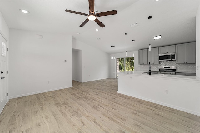 kitchen with stainless steel appliances, sink, vaulted ceiling, light wood-type flooring, and gray cabinets