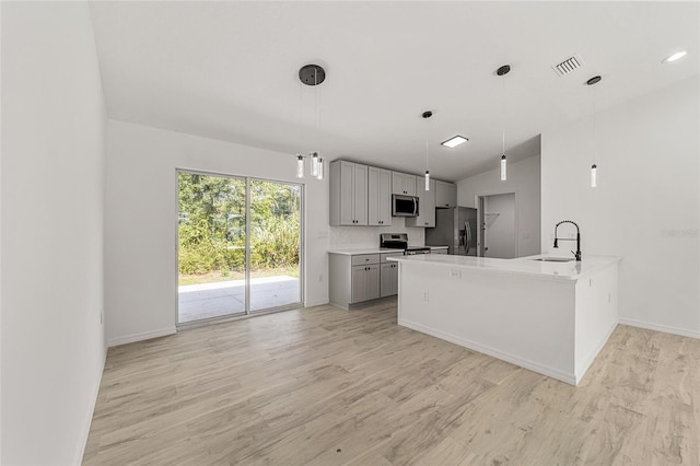 kitchen with gray cabinetry, appliances with stainless steel finishes, sink, kitchen peninsula, and decorative light fixtures