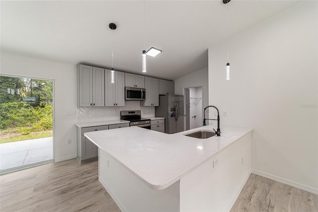 kitchen with sink, decorative light fixtures, stainless steel appliances, and kitchen peninsula