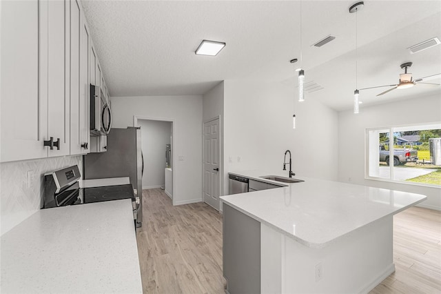 kitchen with hanging light fixtures, stainless steel appliances, sink, vaulted ceiling, and white cabinetry