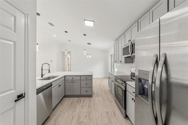 kitchen with light hardwood / wood-style flooring, stainless steel appliances, sink, gray cabinets, and decorative light fixtures