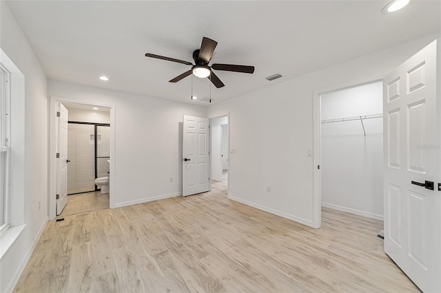 unfurnished bedroom with a walk in closet, ceiling fan, light wood-type flooring, ensuite bathroom, and a closet