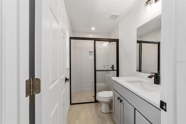 bathroom featuring vanity, wood-type flooring, toilet, and an enclosed shower