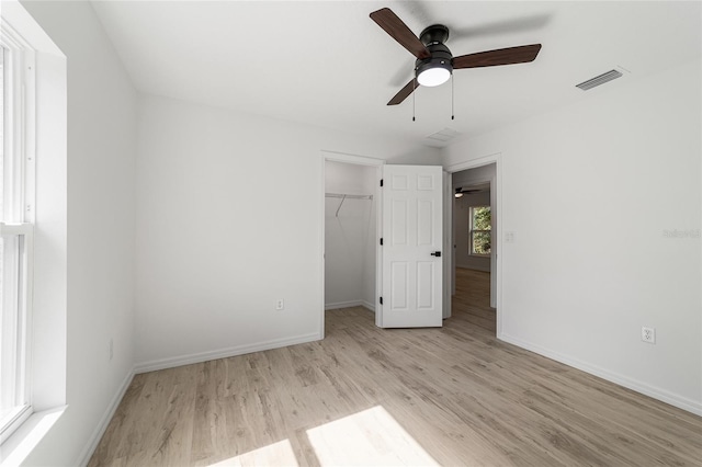 unfurnished bedroom with a spacious closet, ceiling fan, a closet, and light hardwood / wood-style flooring