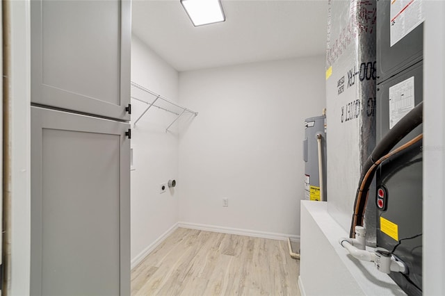 clothes washing area featuring light hardwood / wood-style flooring, electric water heater, and heating unit