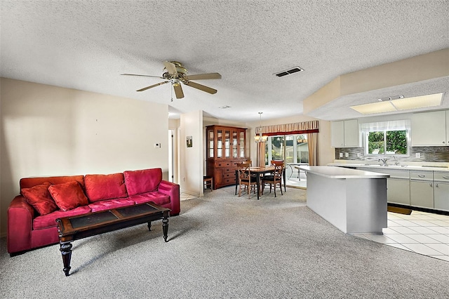 carpeted living room with a textured ceiling, sink, and ceiling fan with notable chandelier