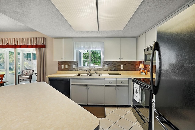 kitchen featuring light tile patterned floors, black appliances, sink, and backsplash