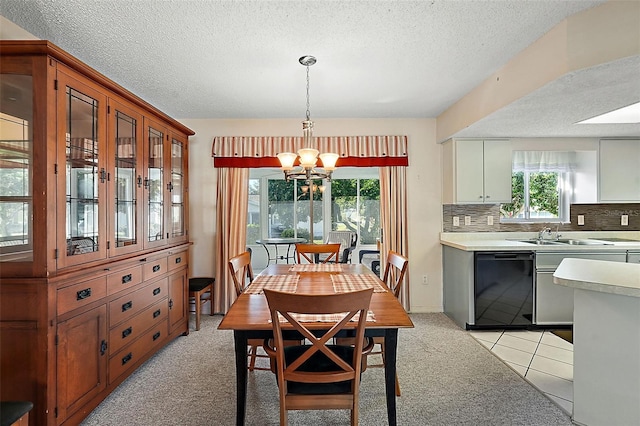 carpeted dining space with sink, a notable chandelier, a textured ceiling, and a skylight