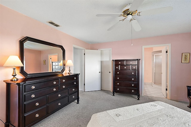 bedroom featuring ensuite bath, a textured ceiling, light colored carpet, and ceiling fan