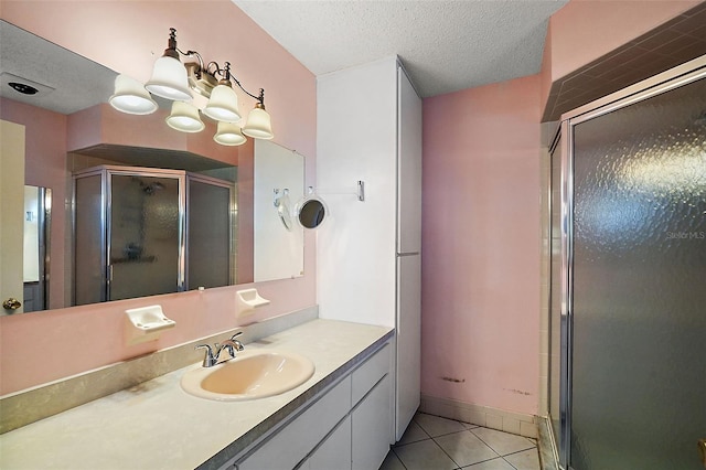 bathroom with vanity, a shower with shower door, a textured ceiling, and tile patterned floors