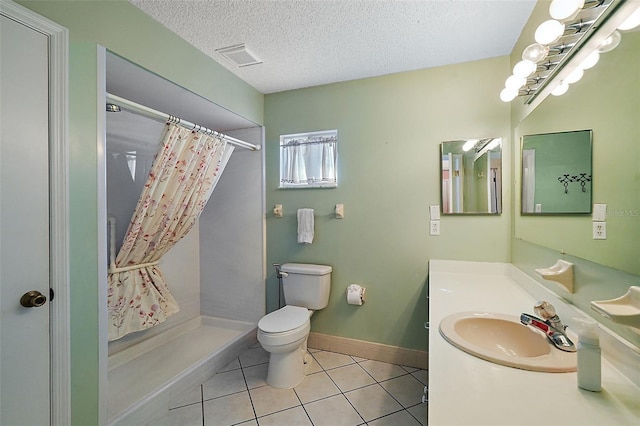 bathroom featuring a textured ceiling, toilet, tile patterned floors, walk in shower, and vanity