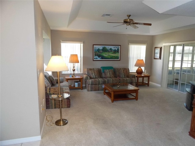 living room with ceiling fan, light carpet, and a tray ceiling