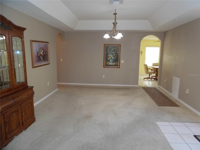 dining space featuring light carpet, a raised ceiling, and a chandelier