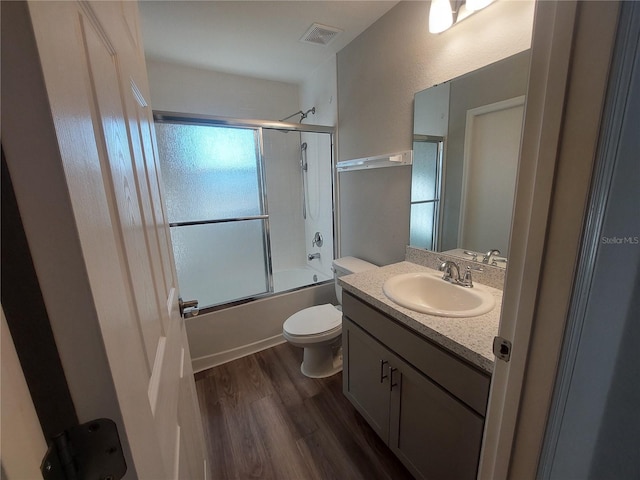 full bathroom featuring shower / bath combination with glass door, vanity, hardwood / wood-style flooring, and toilet