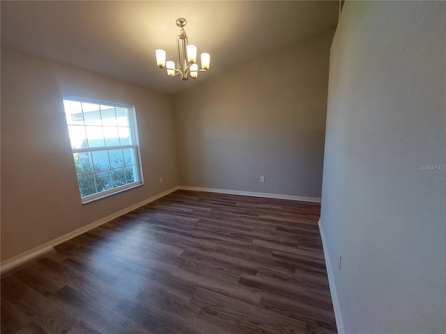 spare room featuring dark wood-type flooring, lofted ceiling, and a notable chandelier