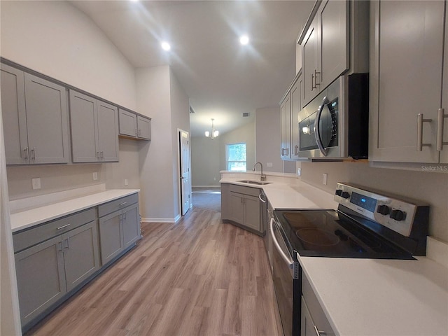 kitchen featuring gray cabinetry, sink, stainless steel appliances, and vaulted ceiling