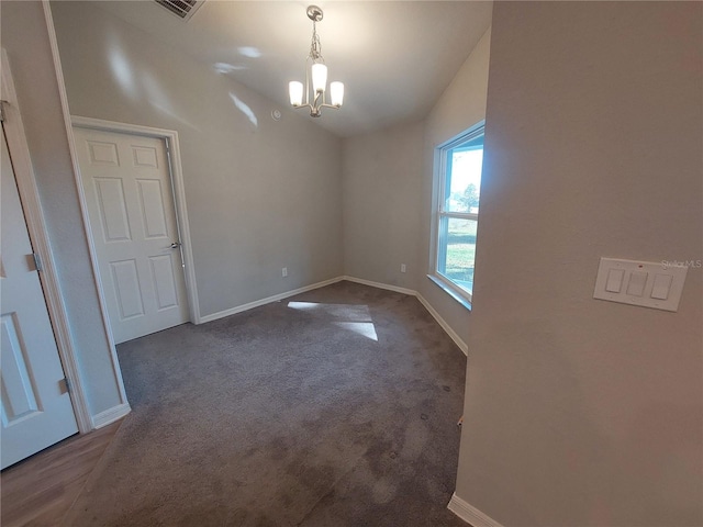 unfurnished dining area featuring dark colored carpet and a chandelier