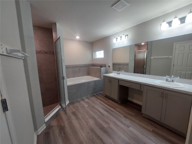 bathroom featuring shower with separate bathtub, vanity, hardwood / wood-style flooring, and a textured ceiling