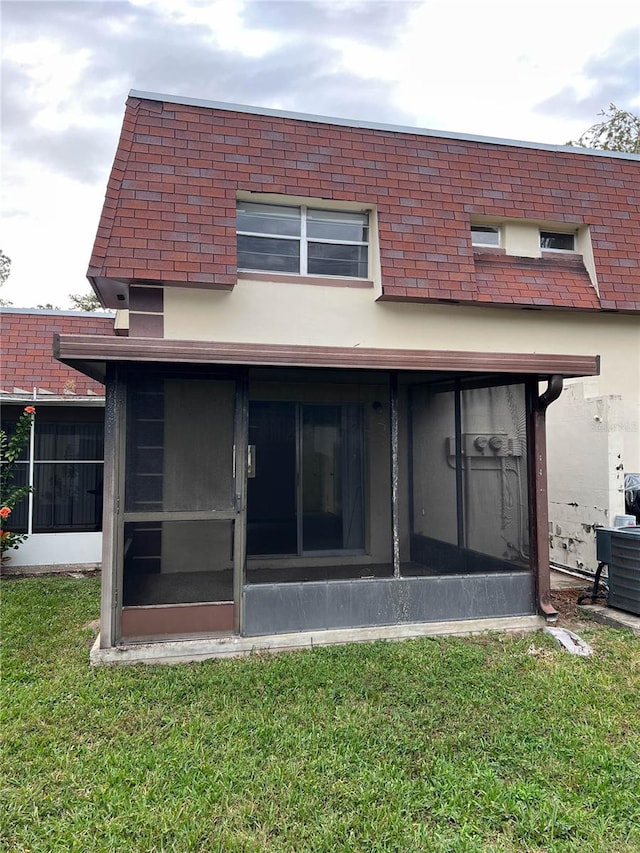 back of property featuring a yard and a sunroom