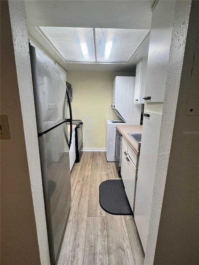 kitchen featuring washer / clothes dryer, light hardwood / wood-style flooring, sink, stainless steel fridge, and white cabinetry