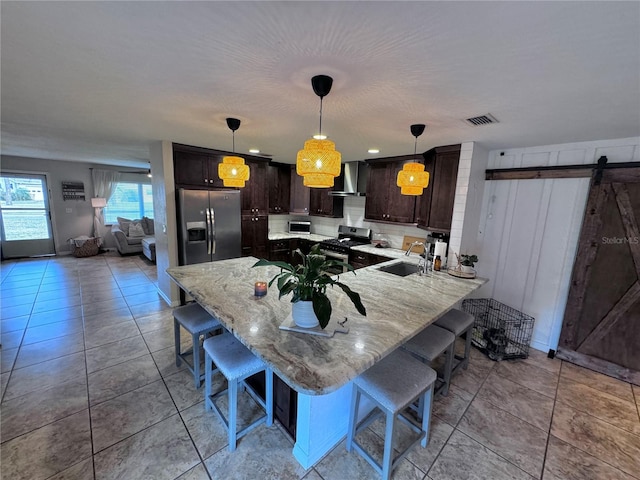 730 NE 18th Ave, Ocala, FL 34470 - kitchen featuring dark brown cabinets, a kitchen breakfast bar, visible vents, wall chimney range hood, and appliances with stainless steel finishes